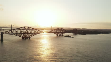 A-job-down-style-drone-shot-at-Forth-Rail-Bridge,-in-Queensferry,-Scotland,-UK-filmed-at-sunset