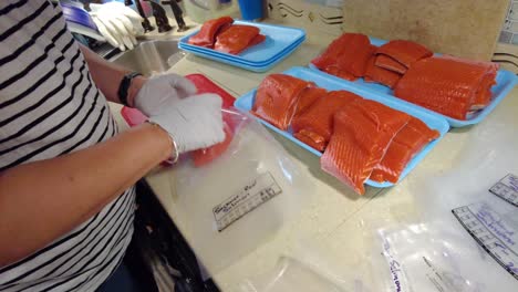 Gloved-hands-putting-fresh-sockeye-salmon-fillets-into-plastic-bags-to-be-vacuum-sealed-later