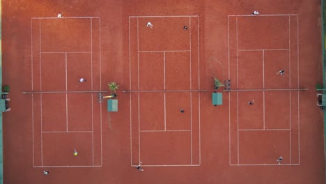 Zeitraffer-Aus-Der-Luft-Von-Oben-Nach-Unten-Von-Tennisspielern,-Die-An-Sonnigen-Tagen-Auf-Mehreren-Plätzen-Spielen