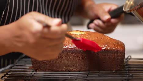 Drizzling-and-brushing-a-sugar-glaze-on-a-freshly-baked-lemon-pound-cake---slow-motion