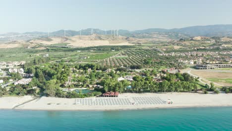 Vista-Panorámica-De-La-Costa-De-Calabria,-Mar-Mediterráneo,-Playa,-Campos-Agrícolas-Y-Turbinas-Eólicas-En-El-Fondo,-Calabria,-Italia