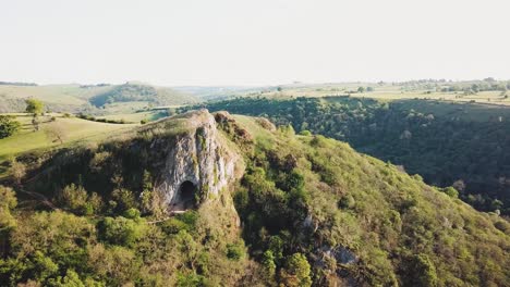 Wide-drone-shot-of-Thor's-Cave,-Ashbourne,-Peak-District-at-sunset