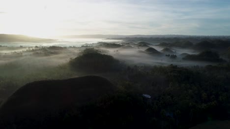 Mist-surrounding-popular-Chocolate-hills-with-bright-morning-sunlight,-Bohol