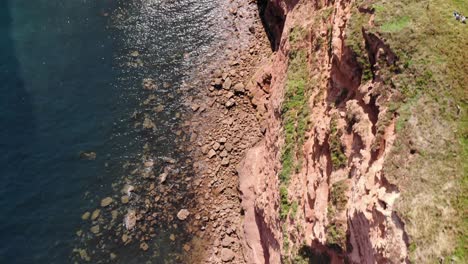 Aerial-Top-Down-View-Of-Sandstone-Cliffs-With-Dark-Turquoise-Waters-In-Devon