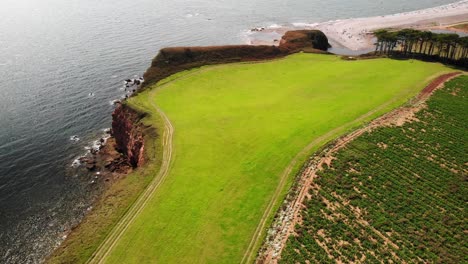 Aerial-Over-Open-Green-Landscape-With-Budleigh-Salterton-Beach-In-Background