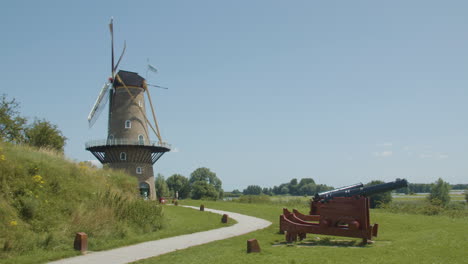 Wide-shot-of-tradition-windmill-blades-spinning-in-the-wind-with-old-cannons-in-the-foregrond