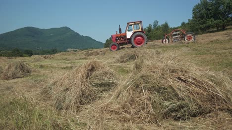 Old-red-tractor-and-threshing-machine-in-golden-hayfield-in-Bulgarian-rural-countryside-meadow