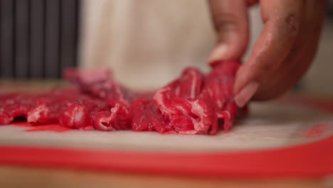 Taking-fresh,-raw,-juicy-slices-of-beef-steak-and-cutting-them-into-cubes---slow-motion-isolated-close-up