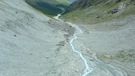 Drone-flight-over-a-winding-glacier-river-through-a-high-mountain-alpine-valley