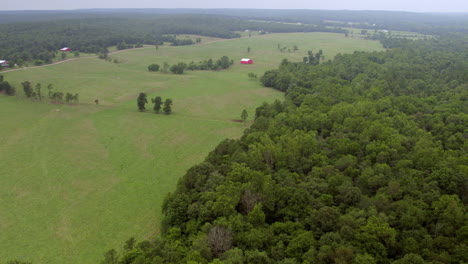 Aerial-of-farmland-and-trees-in-southern-Missouri-with-a-red-barn-trucking-right