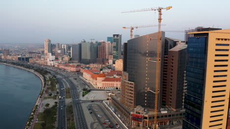 raveling-front,-Luanda-city,-golden-hour-flying-over-Luanda-bay,-Africa