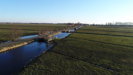 Stolwijk-in-Krimpenerwaard,-Netherlands---Drone-Flying-Low-Above-Vast-Green-Field-With-Frozen-Ditches-And-Wooden-Fences