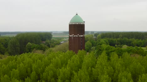 Luftanflug-Auf-Den-Berühmten-Wasserturm-In-Der-Stadt-Axel,-Aufgenommen-An-Einem-Bewölkten-Tag-Mit-Vielen-Umgebenden-Bäumen