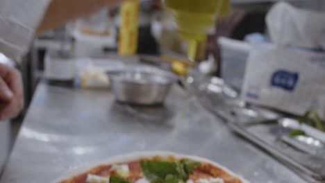 Putting-olive-oil-on-top-of-neapolitan-pizza-on-cooking-table-in-pizzeria