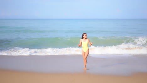 A-sexy-young-in-a-yellow-one-piece-bathing-suit-woman-walks-from-the-surf-and-beach-toward-the-shore