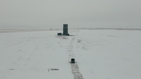 Aerial-following-UTV-side-by-side-through-snow-covered-field-in-winter,-4K