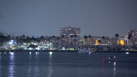 Nachts-Fährt-Ein-Boot-über-Die-Bucht-Mit-Den-Lichtern-Der-Stadt-Und-Des-Hafens-Im-Hintergrund