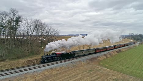 A-Drone-View-of-a-Steam-Locomotive-With-Passenger-Coaches-Approaching-With-a-Full-Head-of-Steam-over-Countryside-on-a-Winter-Day