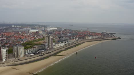 Aerial-high-altitude-orbit-over-the-empty-city-beach-and-waterfront-skyline-in-Vlissingen,-The-Netherlands