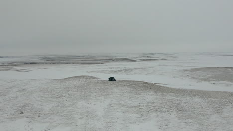 Orbiting-aerial-shot-of-UTV-side-by-side-on-hill-in-barren-tundra,-4K