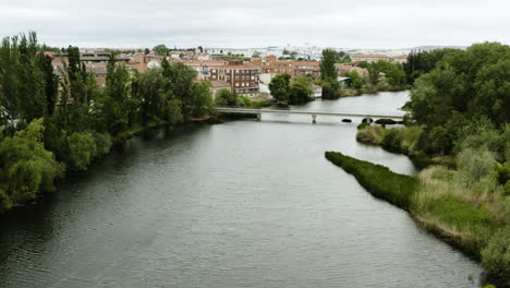 Luftaufnahme-Der-Brücke-über-Den-Fluss-Tormes-Entlang-Der-Insel-Soto-Und-Der-Stadt-In-Salamanca,-Spanien