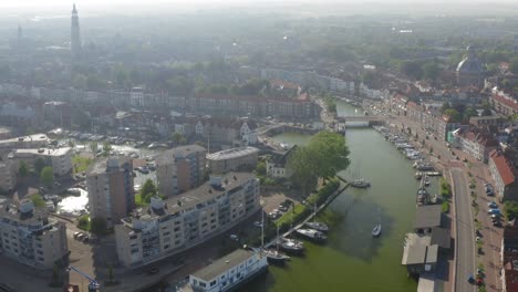 Aerial-shot-of-a-sailboat-sailing-through-the-historical-town-of-Middelburg,-the-Netherlands,-on-a-sunny-summer-evening