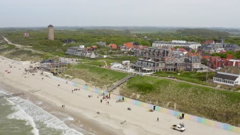 Aerial-shot-of-the-beach,-sea-and-historic-bathing-pavilion-of-the-city-of-Domburg-in-Zeeland,-the-Netherlands,-on-an-overcast-summer-day