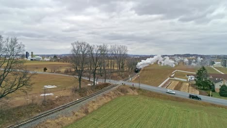 A-Drone-View-of-a-Steam-Locomotive-With-Passenger-Coaches-Approaching-With-a-Full-Head-of-Steam-over-Countryside-on-a-Winter-Day