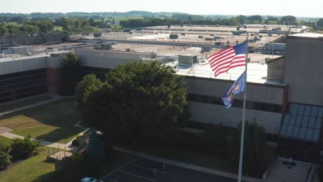 USA-and-Pennsylvania-flags-fly-in-breeze-at-large-industrial-production-facility-workplace
