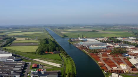 Aerial-shot-of-the-Canal-through-Walcheren-and-industrial-area-in-Zeeland,-the-Netherlands,-on-a-sunny-summer-day