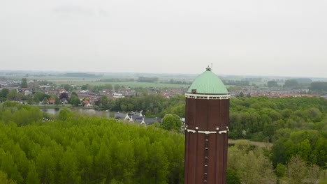 Aerial-revealing-shot-of-the-famous-water-tower-in-the-city-of-Axel-shot-on-a-cloudy-day-with-city-panorama
