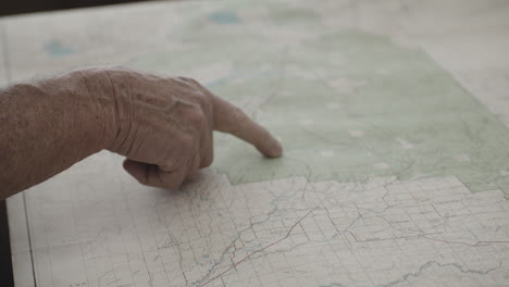 Old-Man's-Index-Finger-Moving-Its-Hand-On-Location-Of-Western-Yellowstone-On-Paper-Map
