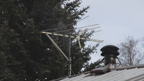 Television-Antenna-With-Smoke-Coming-Out-In-Stove-Chimney-On-A-House-Roof