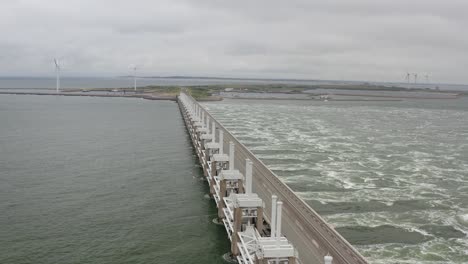 Aerial-shot-flying-backwards-over-the-Eastern-Scheldt-storm-surge-barrier-in-Zeeland,-the-Netherlands,-on-a-stormy-day