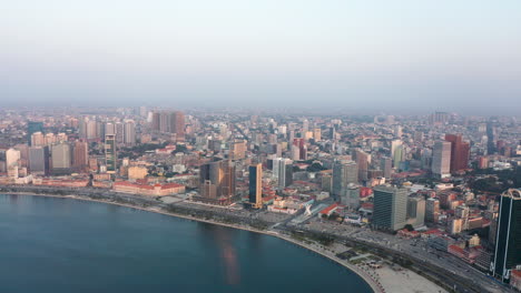 Traveling-right,-Luanda-city,-golden-hour-flying-over-Luanda-bay,-Africa
