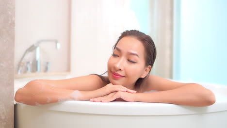 Close-up-of-a-pretty-woman-leans-up-on-her-arms-and-elbow-while-she-enjoys-her-bubble-bath