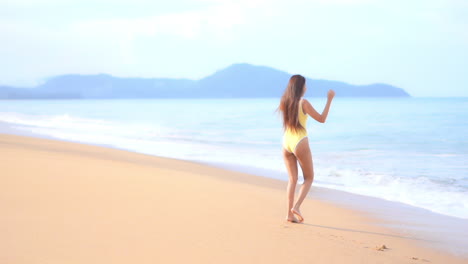 A-pretty-young-woman-walks-forward-and-backward,-playing-in-the-incoming-surf