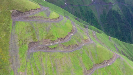 Wide-rotating-drone-shot-of-vehicle-driving-on-the-Road-to-Tusheti,-one-of-the-worlds-most-dangerous-roads