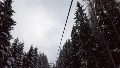 Austria,-Semmering,-Stuhleck-ski-resort,-cable-car-is-moving-on-the-wire-ropes-and-passing-through-the-elongation-with-snowy-conifers-and-sky-in-the-background