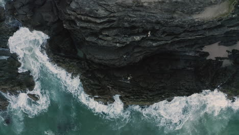 4k-Top-view-drone-shot-of-hikers-climbing-on-a-rock-side-on-a-small-island-close-to-Byron-Bay,-Australia