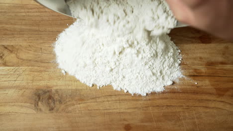 Close-Up:-Chef-pouring-flour-in-a-mound-on-a-wooden-table