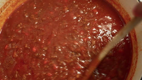 Mixing-Italian-Bolognese-Sauce-being-cooked-in-a-cast-iron-pot-Chef-stirring-the-most-famous-Italian-sauce