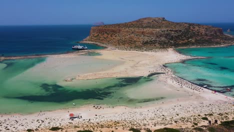 Aerial-panning-across-Balos-Beach-and-Lagoon-with-turquoise-water,-mountains-and-cliffs-in-Crete,-Greece