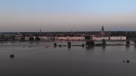 Vast-water-floodplains-in-front-of-countenance-of-Dutch-Hanseatic-medieval-tower-town-Zutphen-in-The-Netherlands-during-extreme-high-water-levels-of-river-IJssel