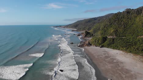 Drohnenblick-Auf-Die-Ostküste-Neuseelands-Mit-Langsamen-Wellen-Und-Felsigem-Strand-An-Klaren-Sommertagen-In-4k