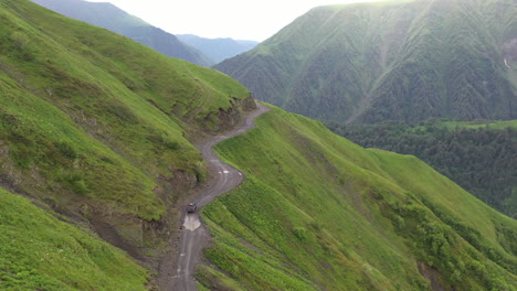Cinematic-descending-drone-shot-of-vehicle-driving-on-the-Road-to-Tusheti,-in-the-Caucasus,-one-of-the-worlds-most-dangerous-roads