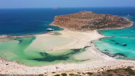Aerial-revealing-Balos-Beach-and-Lagoon-with-turquoise-water,-mountains-and-cliffs-in-Crete,-Greece