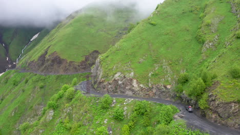 Desecending-drone-shot-of-a-vehicle-driving-on-the-Road-to-Tusheti-on-the-Abano-pass-in-Georgia