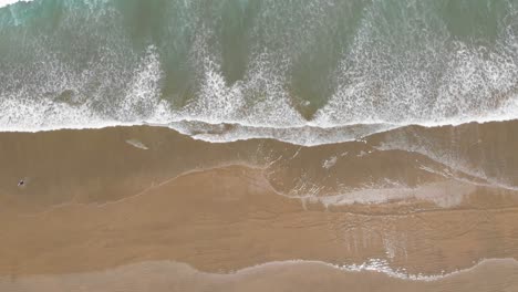 View-from-the-sky-down-on-the-ocean-waves-and-sandy-beach-on-a-warm-summer-day-filmed-from-great-height-in-4k