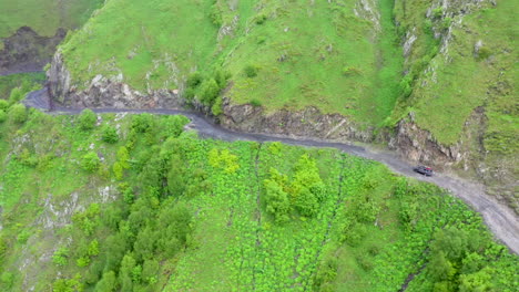 Revealing-drone-shot-of-a-vehicle-driving-on-the-Road-to-Tusheti-on-the-Abano-pass-in-Georgia